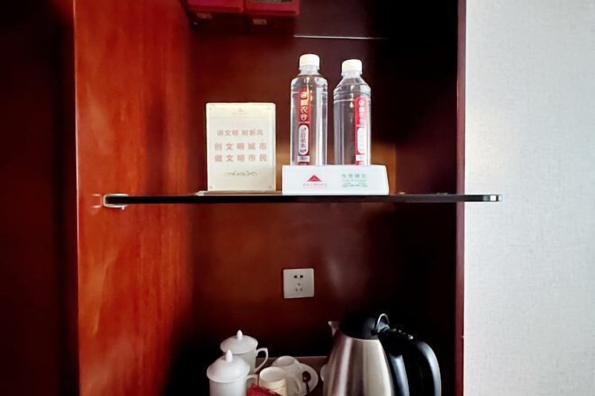Una puerta de madera con un estante superior que contiene un cartel, dos botellas y una caja pequeña.