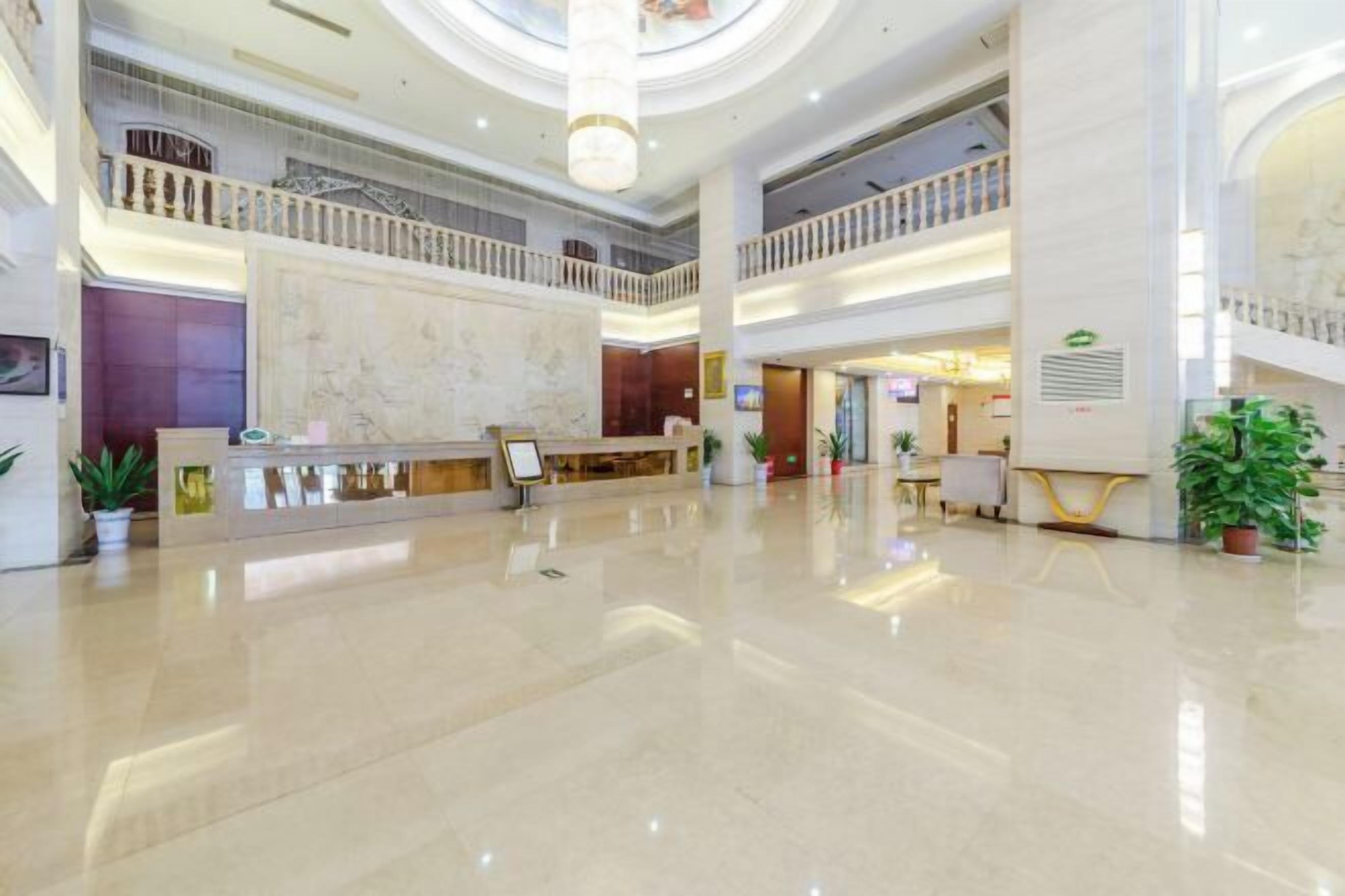 Un vestíbulo espacioso con una recepción de mármol, varios pisos y un atrium central con techo de cristal.