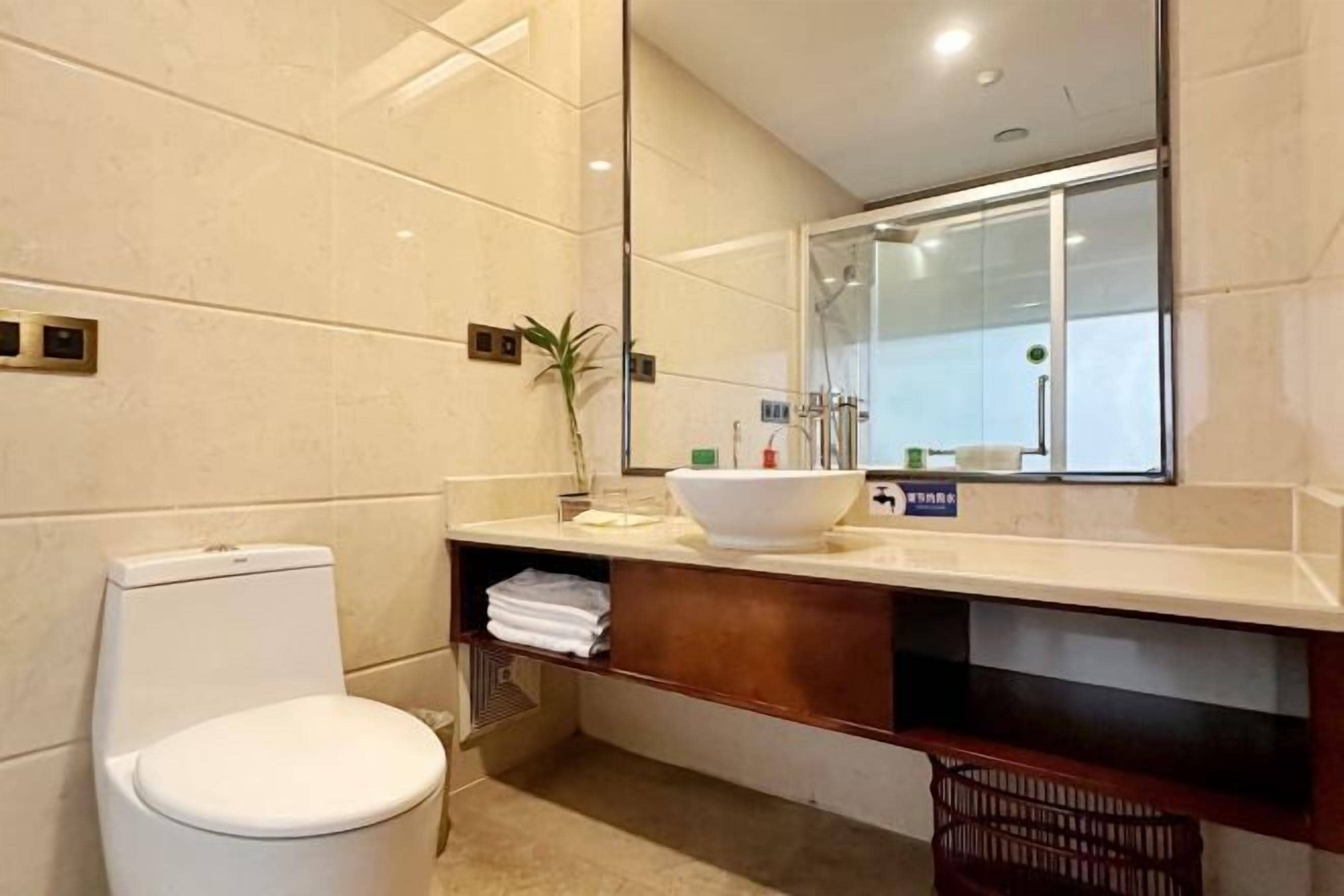 A modern bathroom with a toilet, a large mirror, and a sink with a white basin.