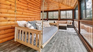 Een slaapkamer in een blokhut met een bed, een schommelstoel en een bank.