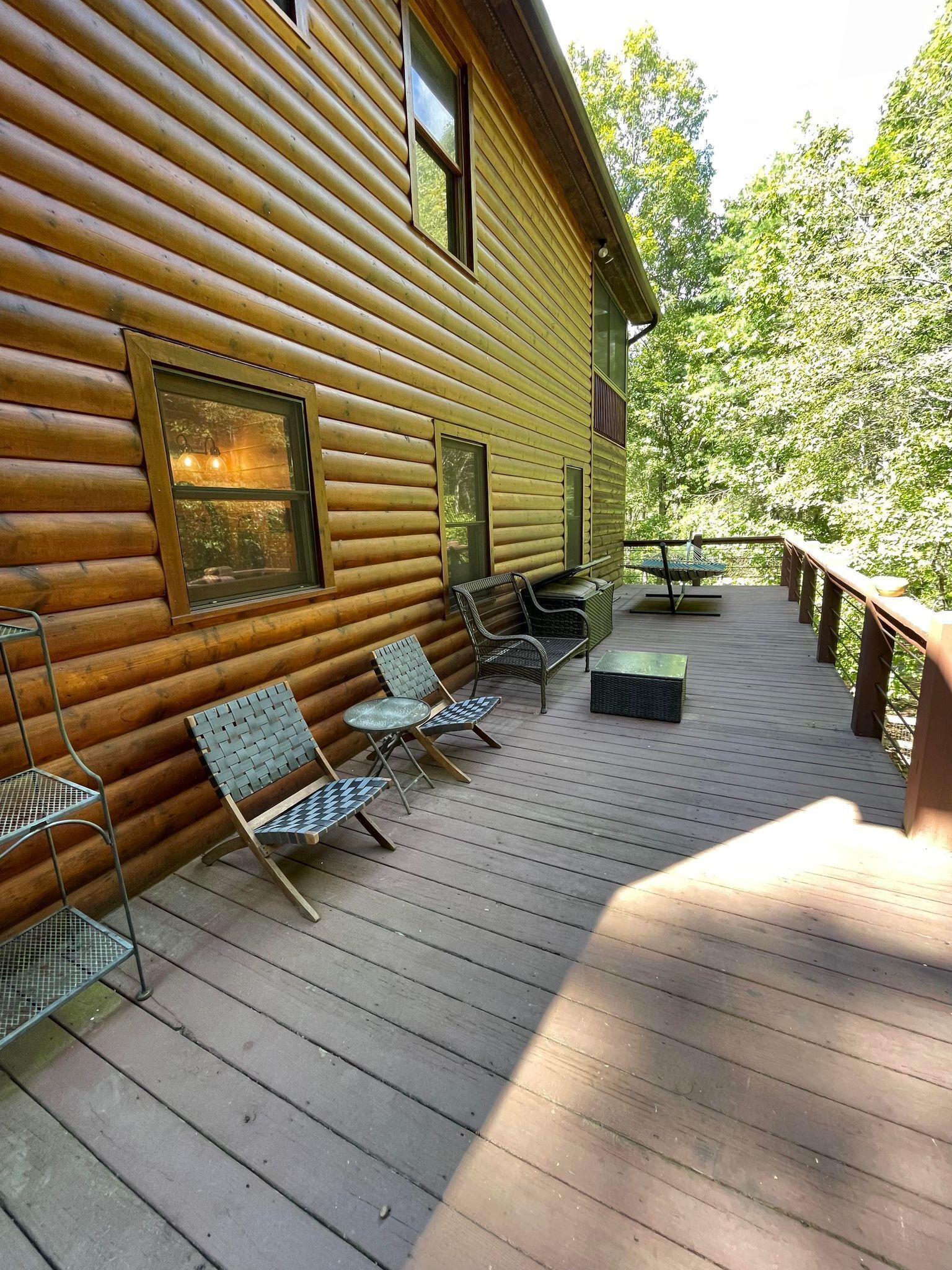 Eine Holzhütte mit einer Terrasse, ausgestattet mit Metallstühlen und einem Tisch.