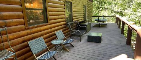 Eine Holzhütte mit einer Terrasse, ausgestattet mit Metallstühlen und einem Tisch.