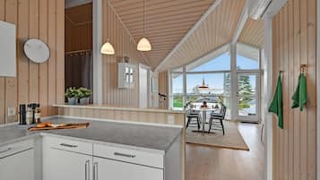 Une cuisine moderne avec des murs en bois, une grande fenêtre et un coin repas offrant une vue agréable.
