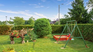 A well-maintained garden with a swing set, a wooden play structure, and neatly trimmed hedges. - Nice apartment in Kopalino with WiFi (Kopalino)
