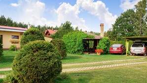 A residential property with a garden, a covered outdoor seating area, a red car, and a yellow building. - Nice apartment in Kopalino with WiFi (Kopalino)