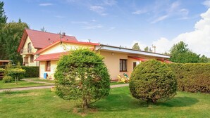 A two-story house with a red-tiled roof, a well-maintained lawn, and several trees. - Nice apartment in Kopalino with WiFi (Kopalino)