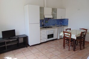 Een kleine keuken met een eethoek, een televisie en een betegelde vloer.