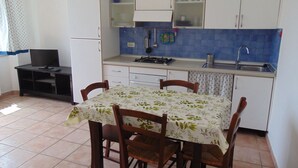 Una cocina compacta con estufa a gas, pileta y gabinetes blancos.
