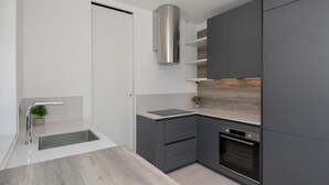 Ett modernt kök med en inbyggd ugn, en fläktkåpa i rostfritt stål och en minimalistisk design.
