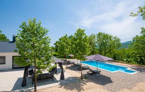Relax by the serene pool surrounded by lush greenery and lounge chairs.