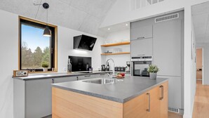 A modern kitchen with a large island, built-in appliances, and a window with a view of trees. - 3 bedroom nice home in Rømø (Rømø)