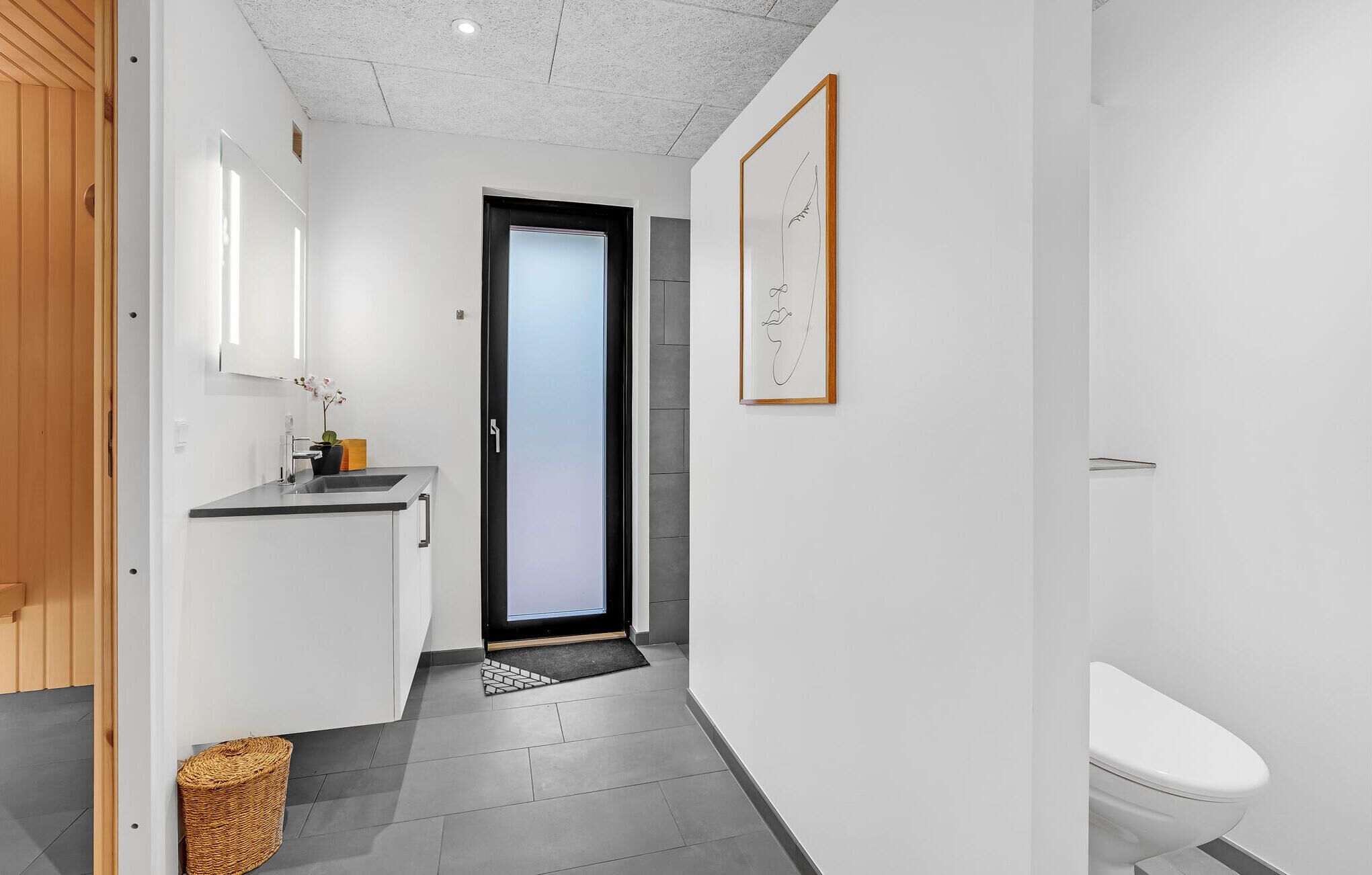 Een moderne badkamer met toilet, wastafel en een kunstwerk in een lijst aan de muur.