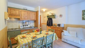 Una cocina compacta con armarios de madera, una estufa y una mesa de comedor con platos de fruta.