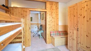 Una habitación de madera con una cama litera, una mesita con un árbol de Navidad y un banco con cojín de cuadros.