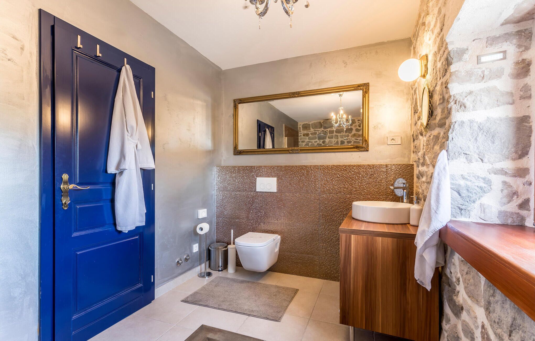A bathroom with a blue door, a white toilet, a sink, and a mirror.
