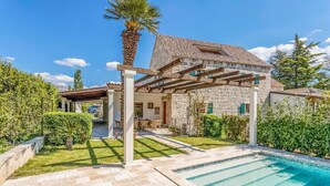 A stone house with a tiled roof, a covered patio, and a swimming pool. - Stunning home in Solin (Solin)
