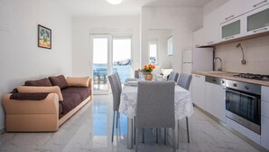 A modern apartment with a dining area, kitchen, and a balcony with a view of the sea. - Cozy apartment in Rogoznica with WiFi (Rogoznica)
