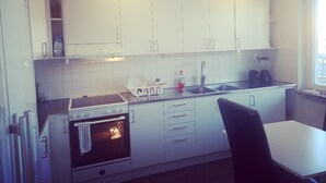 Una cocina con armarios blancos, una estufa, un lavabo y una ventana.
