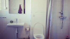 Un baño con lavamanos, inodoro y ducha blancos.