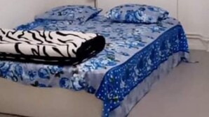 Un dormitorio con cama, ventana y una lámpara en el techo.