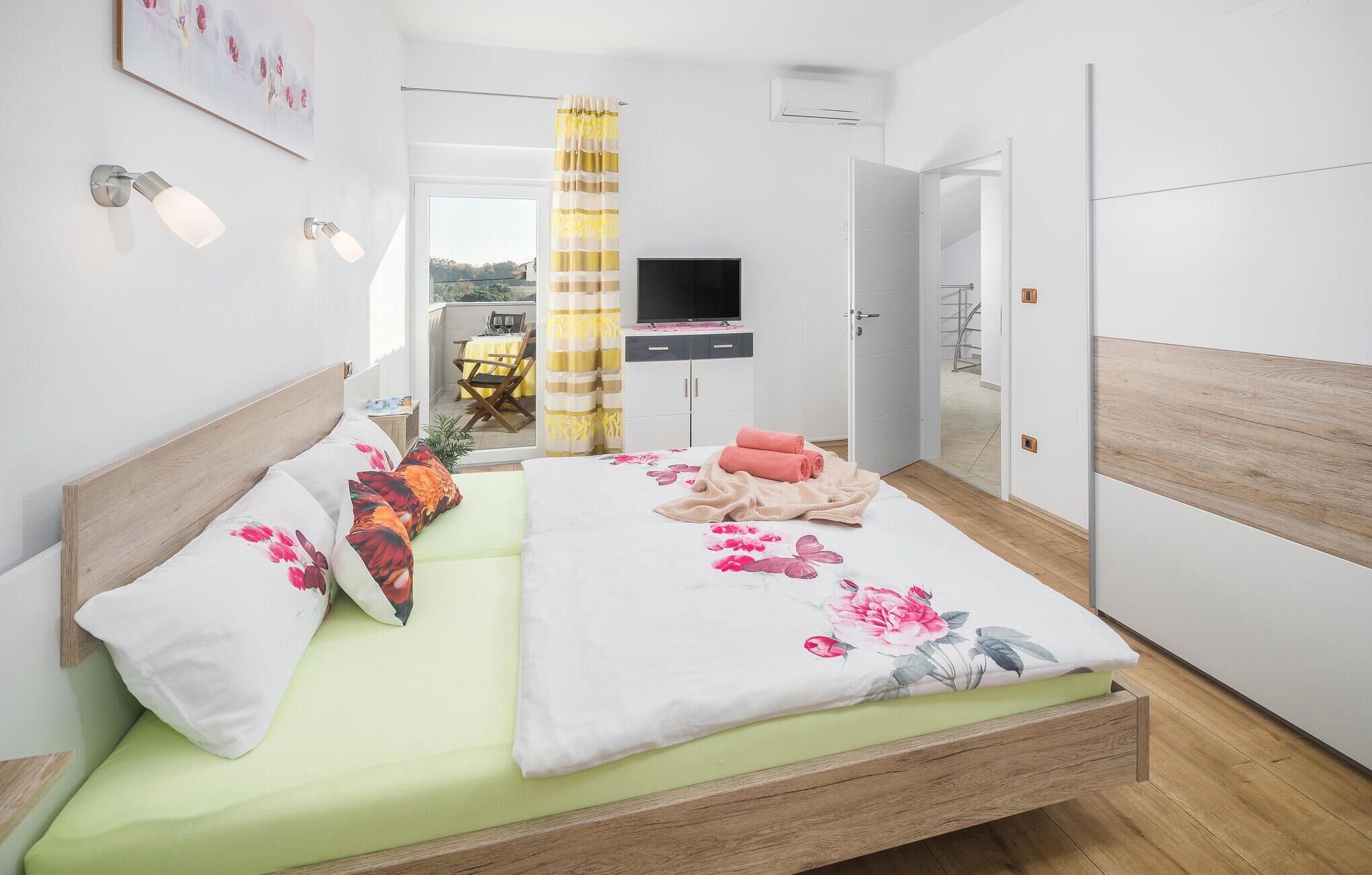 Une chambre moderne avec un lit, une télévision et un balcon donnant sur une belle vue.