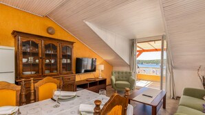 Ruokailutila, jossa on kahdelle katettu pöytä, televisio ja näkymä merelle.