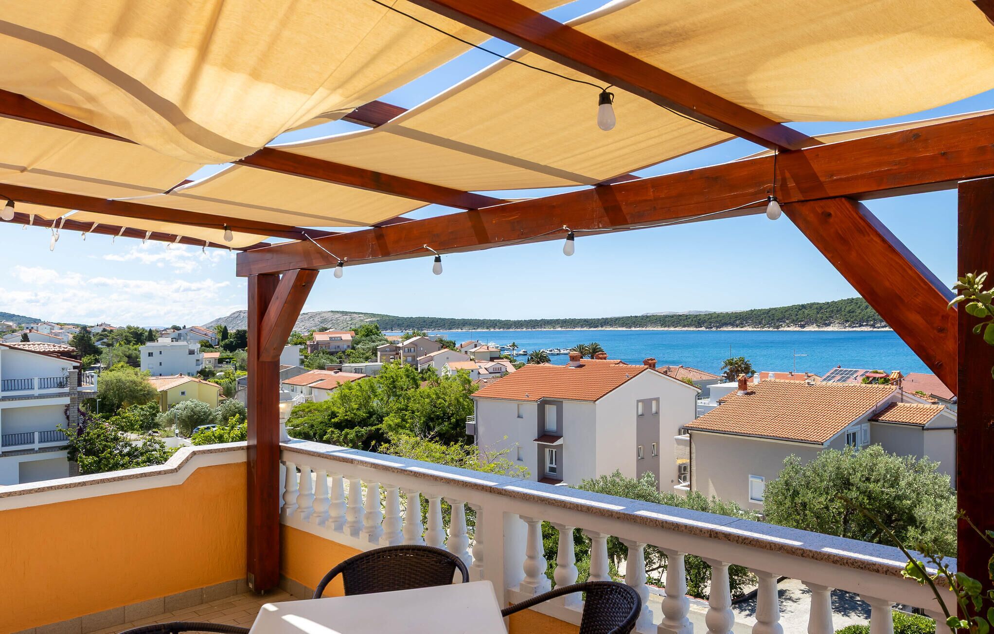 Un balcone con vista sul mare, travi in legno e un tavolo con sedie.