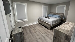 A bedroom with a bed, wooden headboard, and a nightstand with a lamp. - The Lakeside Cottage in Stow! (Stow)