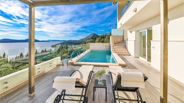 Una terraza en la azotea con piscina, mobiliario exterior y vistas panorámicas de un lago y montañas.