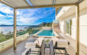 A rooftop terrace with a pool, outdoor seating, and a scenic view of a lake and mountains.