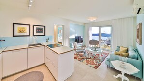 Un apartamento moderno con cocina, comedor y sofá con vista al mar.