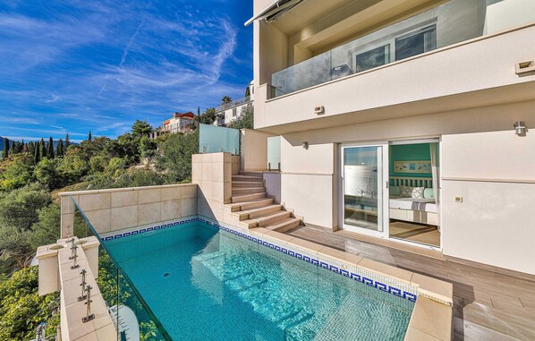 A modern two-story house with a swimming pool, a staircase leading to the upper floor, and a view of the surrounding landscape.