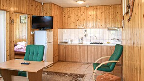 A compact kitchen with wooden cabinets, a built-in TV, a refrigerator, and a dining area with a table and two chairs. - Beautiful apartment in Kopalino (Kopalino)