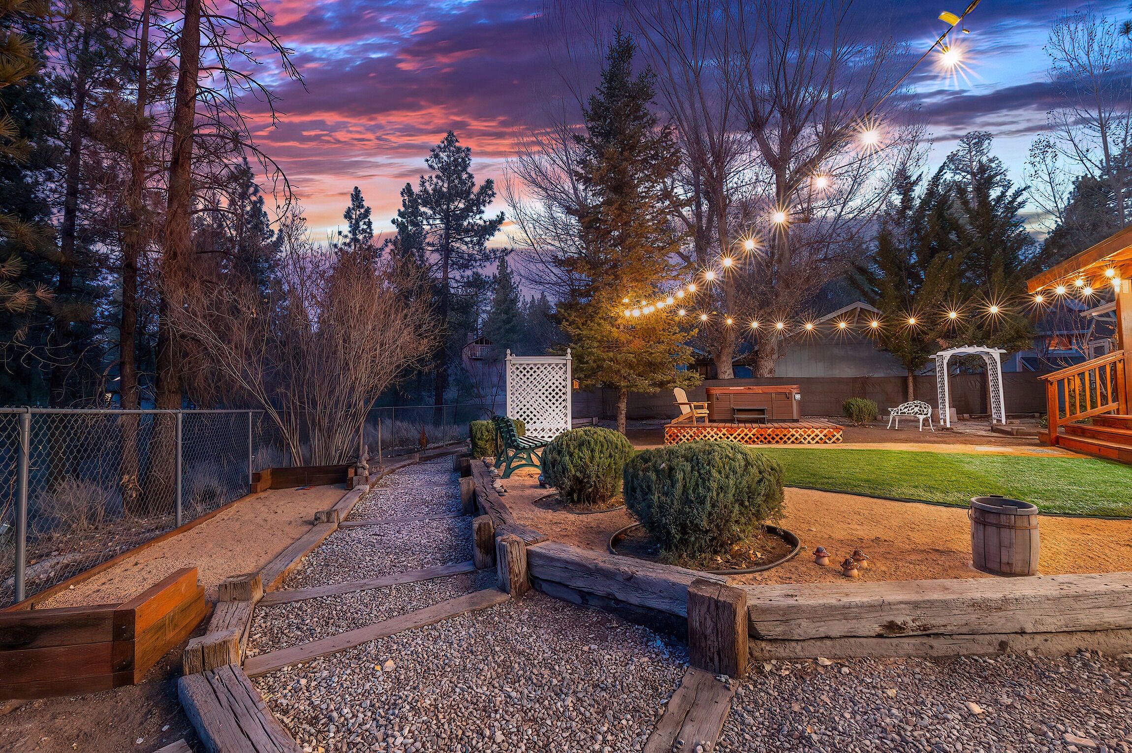 A backyard with a wooden deck, a lawn, and a pergola.