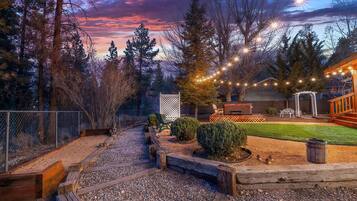 A backyard with a wooden deck, a lawn, and a pergola.
