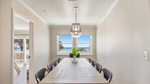 A dining area with a wooden table, chairs, and a hanging light fixture. - 5 STAR BEACH FRONT RENOVATED TOWNHOME with BEACH SERVICE on Okaloosa Island (Fort Walton Beach)