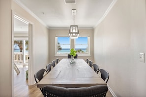 A dining area with a wooden table, chairs, and a hanging light fixture. - 5 STAR BEACH FRONT RENOVATED TOWNHOME with BEACH SERVICE on Okaloosa Island (Fort Walton Beach)