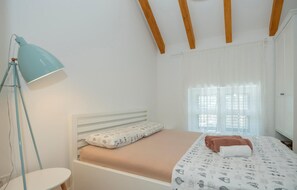 A bedroom with a single bed, a bedside lamp, a window with curtains, and a wardrobe. - Lovely home in Glavina donja (Glavina donja)