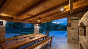 An outdoor dining area with a wooden table and benches, a brick wall, and a stone archway. - Lovely home in Glavina donja (Glavina donja)