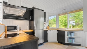 A modern kitchen with a microwave, stove, and dishwasher. There is a window with a view of greenery outside.