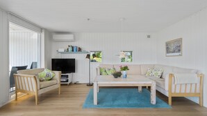 A spacious living room with a large TV, two sofas, a coffee table, and a blue rug.