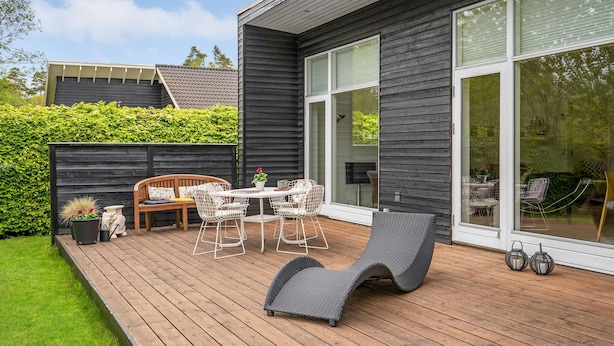 A deck with outdoor furniture, a wooden table, and chairs. - 3 bedroom stunning home in Ebeltoft (Ebeltoft)
