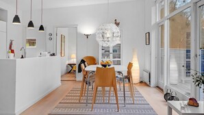 A modern, well-lit dining area with a chandelier, wooden chairs, and a central table. - 3 bedroom stunning home in Ebeltoft (Ebeltoft)