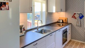 Een moderne keuken met een ingebouwde oven, een spoelbak en een raam met uitzicht op een terras.