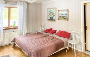 Classic bedroom with a large bed, wooden chair, and framed paintings.