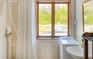 Enjoy a serene bathroom retreat with a forest view, featuring a sink, shower, and toilet.