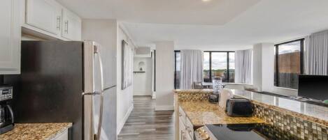 A modern kitchen with stainless steel appliances, a tiled backsplash, and a view of the outdoors through large windows.