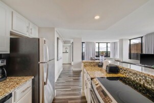 A modern kitchen with stainless steel appliances, a tiled backsplash, and a view of the outdoors through large windows.