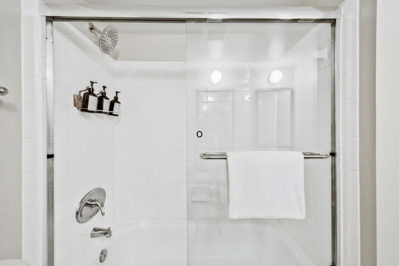 Une salle de bain moderne avec une douche à parois de verre, des robinetteries chromées et une serviette blanche posée sur un porte-serviettes.