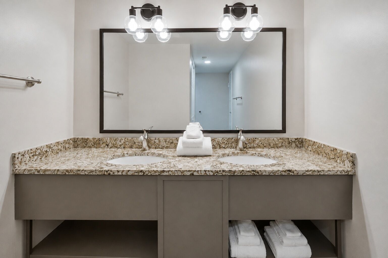 A bathroom with a double sink vanity, a large mirror, and overhead lighting.